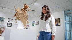 Image of a student standing by artwork in the Finley Gallery