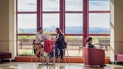 Two students sitting in the CELS building discussing things.