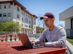 student with laptop sitting outside