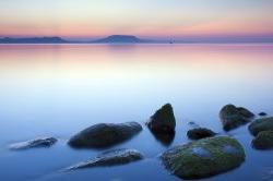 view of a lake at sunset with some rocks