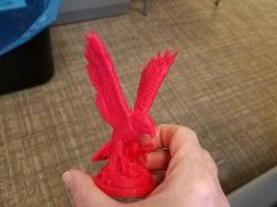 Hand holding a small 3D-printed Red Hawk statue