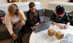 Three female students sit at laptop, working on group project, in the Feliciano Center office