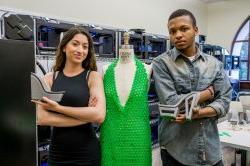 Male and female student pose with 3D printed green dress, and gray shoes