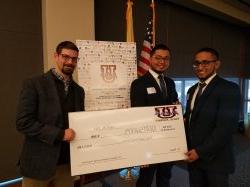 Two students and professor hold oversized prize check.