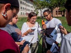 Group of students conducting a science experiment about physics outside, while huddled in a group.