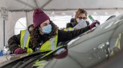 worker places sticker on vehicle's windshield