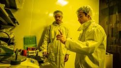 Two men in lab coats under the yellow light of the lab.