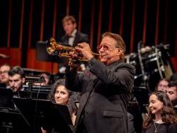 Arturo Sandoval plays the trumpet with students in the University Wind Symphony seated behind him.