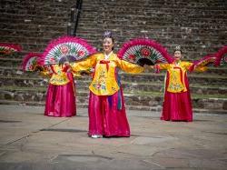 Three dancers wearing traditional Korean dress and with large fans.