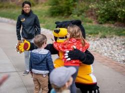 A bear mascot hugs children.